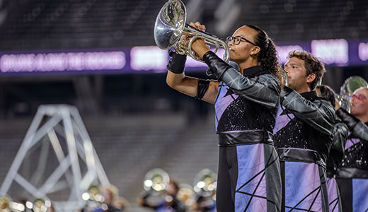 Drum Corp International trumpet players performing at a stadium